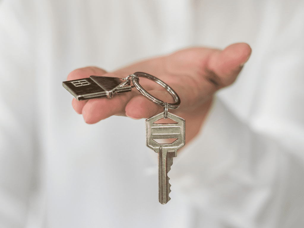 Person hand out house keys with house shaped keychain